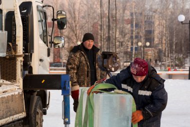 Kışın çalışan işçiler, bir inşaat alanındaki buz bloğunun altına fırlatılan rüzgar kıyafetlerini giyerler.