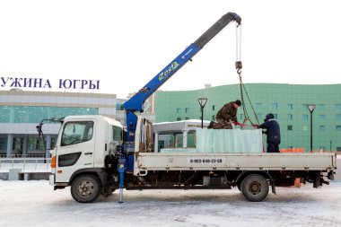 İki montaj işçisi bir arabanın gövdesinden buz kalıplarını boşaltıyor.