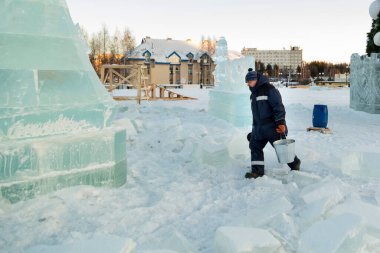 Buz kasabasının toplanma yerinde elinde kova olan bir işçi.