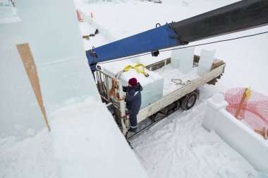 Kırmızı örgü şapkalı çalışan bir derleyicinin portresi buz panellerini boşaltıyor.