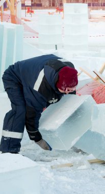Bir işçi, buz kasabasının toplanma yerinde elleri ile bir buz bloğunu sürüklüyor.