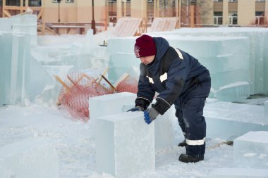 Bir işçi, buz kasabasının toplanma yerinde elleri ile bir buz bloğunu sürüklüyor.