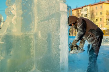 Heykeltıraş, buzdan bir buz figürünü Noel için elektrikli testere ile kesiyor.