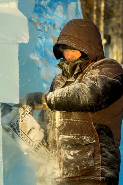 Heykeltıraş, buzdan bir buz figürünü Noel için elektrikli testere ile kesiyor.