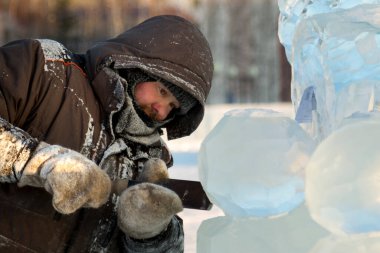 Heykeltıraş buz kalıbından bir buz kalıbını kesiyor.