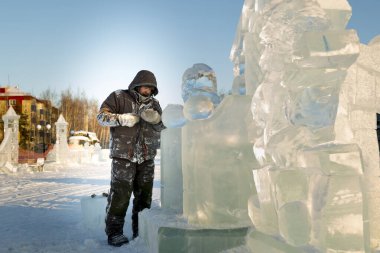 Heykeltıraş, buzdan bir buz figürünü Noel için elektrikli testere ile kesiyor.