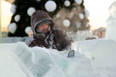 Heykeltıraş, buzdan bir buz figürünü Noel için elektrikli testere ile kesiyor.