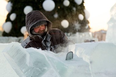 Heykeltıraş, buzdan bir buz figürünü Noel için elektrikli testere ile kesiyor.