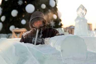 Heykeltıraş, buzdan bir buz figürünü Noel için elektrikli testere ile kesiyor.