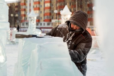 Heykeltıraş, buzdan bir buz figürünü Noel için elektrikli testere ile kesiyor.