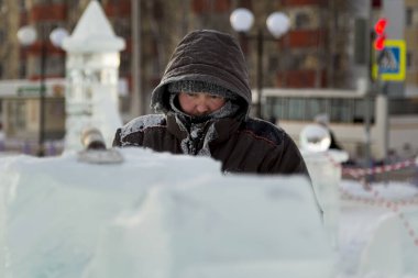 Heykeltıraş, buzdan bir buz figürünü Noel için elektrikli testere ile kesiyor.