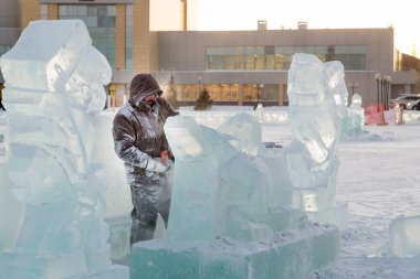 Heykeltıraş, buzdan bir buz figürünü Noel için elektrikli testere ile kesiyor.