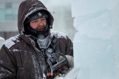 Heykeltıraş, buzdan bir buz figürünü Noel için elektrikli testere ile kesiyor.