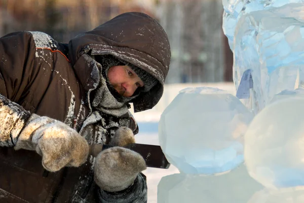 Heykeltıraş buz kalıbından bir buz kalıbını kesiyor.