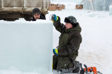 İşçiler buz şehrinin montaj alanındaki buz bloğunu mezurayla işaretliyor