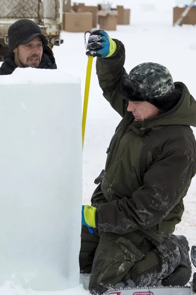 İşçiler buz şehrinin montaj alanındaki buz bloğunu mezurayla işaretliyor