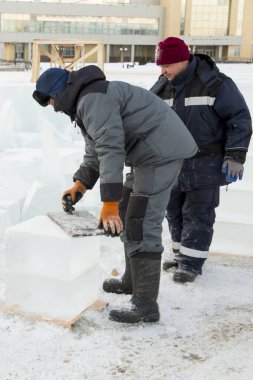 İnşaatçı kar teli fırçasıyla buz panelini temizliyor.