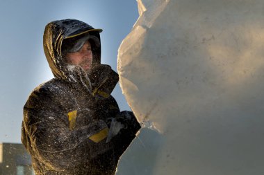 Heykeltıraş buz kalıbından bir buz kalıbını kesiyor.