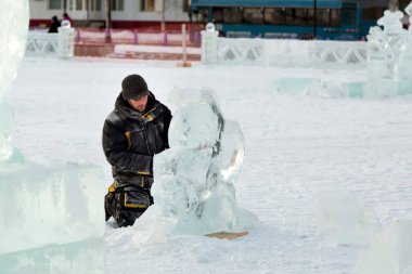Heykeltıraş buz kalıbından bir buz kalıbını kesiyor.