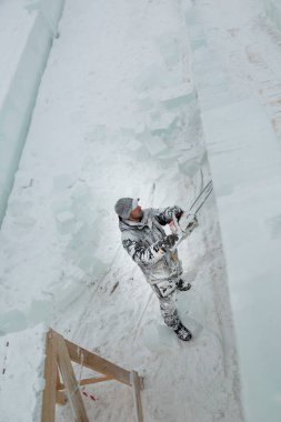 Heykeltıraş, gelecekteki kompozisyonun hatlarını bir buz tabakasında testere ile keser.