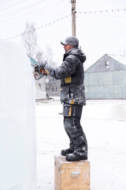 Heykeltıraş, gelecekteki kompozisyonun hatlarını bir buz tabakasında testere ile keser.