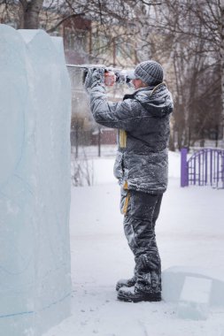 Heykeltıraş, gelecekteki kompozisyonun hatlarını bir buz tabakasında testere ile keser.