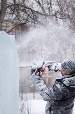 Heykeltıraş, gelecekteki kompozisyonun hatlarını bir buz tabakasında testere ile keser.
