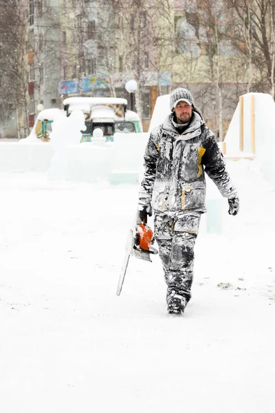 İşçi elinde testere ile buz şehre gider
