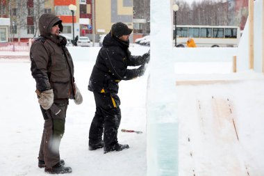 Heykeltraşlar Noel için buz paneline yontulmuş bir heykel oyuyorlar.