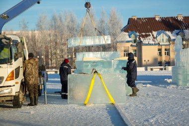 Birleştiriciler vinç kullanarak bir arabadan buz panelleri indirir.
