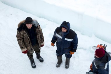 Montaj alanında ellerinde mezurayla çalışan işçiler.