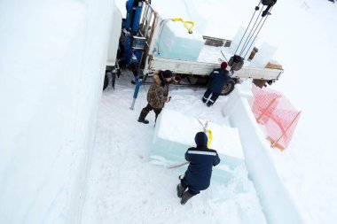 Birleştiriciler vinç kullanarak bir arabadan buz panelleri indirir.