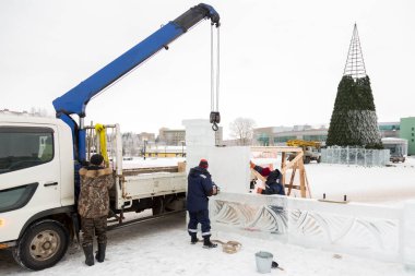 Yapımı devam eden Noel ağacının arka planında buz kasabasının enstalasyon yerinde üç işçi