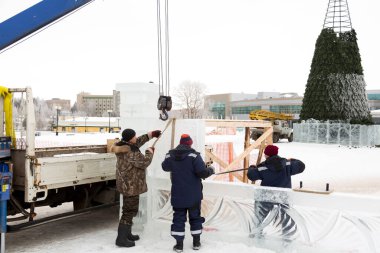 Yapımı devam eden Noel ağacının arka planında buz kasabasının enstalasyon yerinde üç işçi