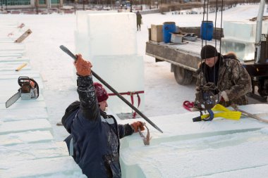 Bir işçi buz kalıplarını levyeyle itiyor.