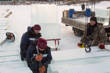 Bir işçi buz kalıplarını levyeyle itiyor.