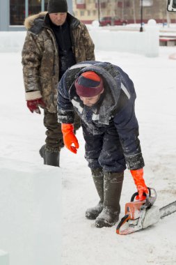 Montaj alanında elinde testere olan bir işçi.
