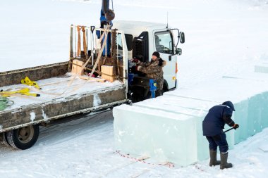 Bir işçi buz kalıplarını levyeyle itiyor.