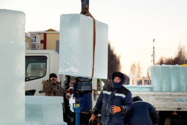 İki montaj işçisi bir arabanın gövdesinden buz kalıplarını boşaltıyor.