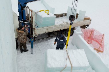 Kamyon vinci ile buz kalıplarını boşaltıyorlar.
