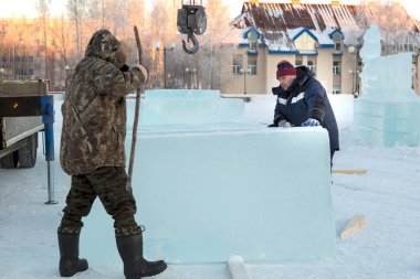 Elinde levyeyle buz kasabasının inşaat alanında çalışan bir işçi.