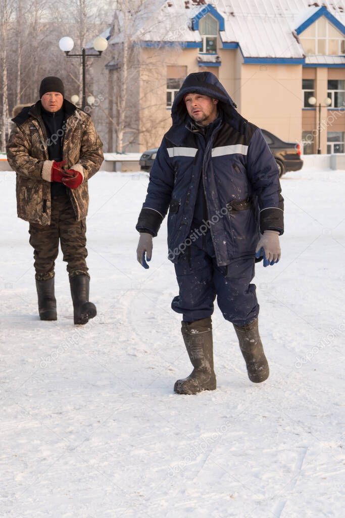 Two assemblers walk along the construction site of the ice town