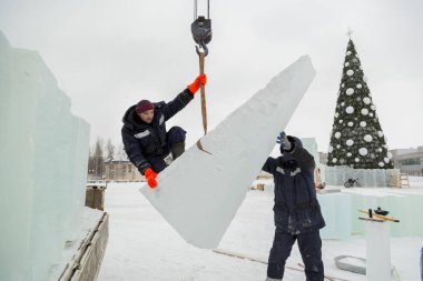 Kurucu buz bloğunda duruyor, bant askısına tutunuyor.