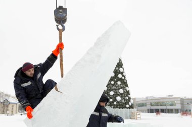 Kurucu buz bloğunda duruyor, bant askısına tutunuyor.