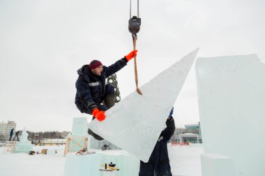 Kurucu buz bloğunda duruyor, bant askısına tutunuyor.