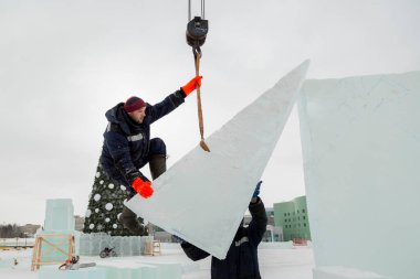 Kurucu buz bloğunda duruyor, bant askısına tutunuyor.