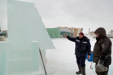 Buz panelinde ortağı olan elektrikli testereli bir işçi.