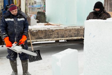 Buz panelinde ortağı olan elektrikli testereli bir işçi.