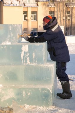 Heykeltıraş, Noel için bir buz kalıbını keskiyle kesiyor.