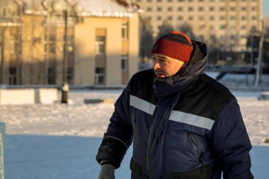 İş yerinde mavi ceketli ve örgü şapkalı bir işçinin yakın çekimi.